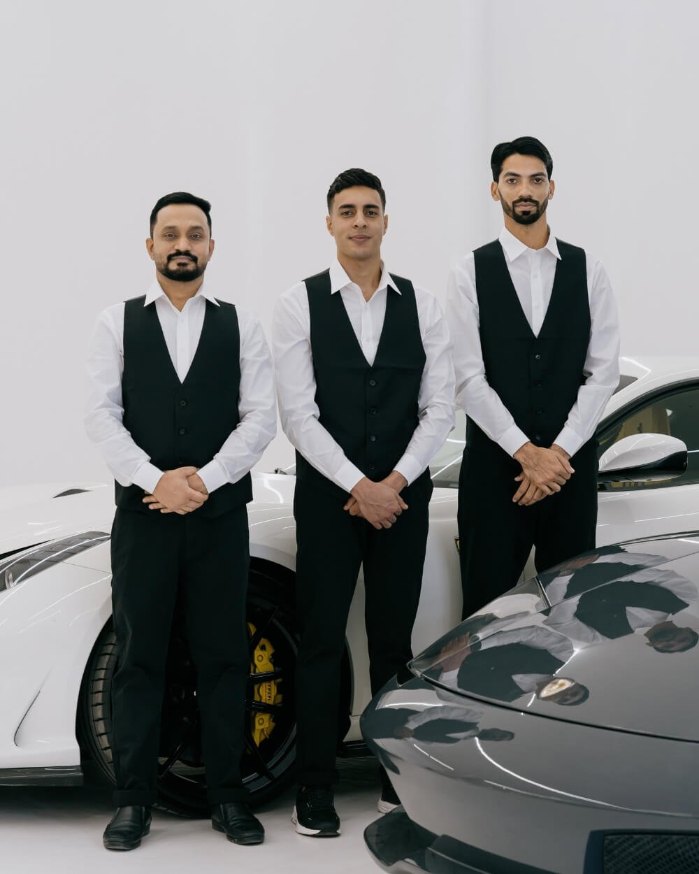 Elegant Luxe Valet Services team standing next to luxury cars