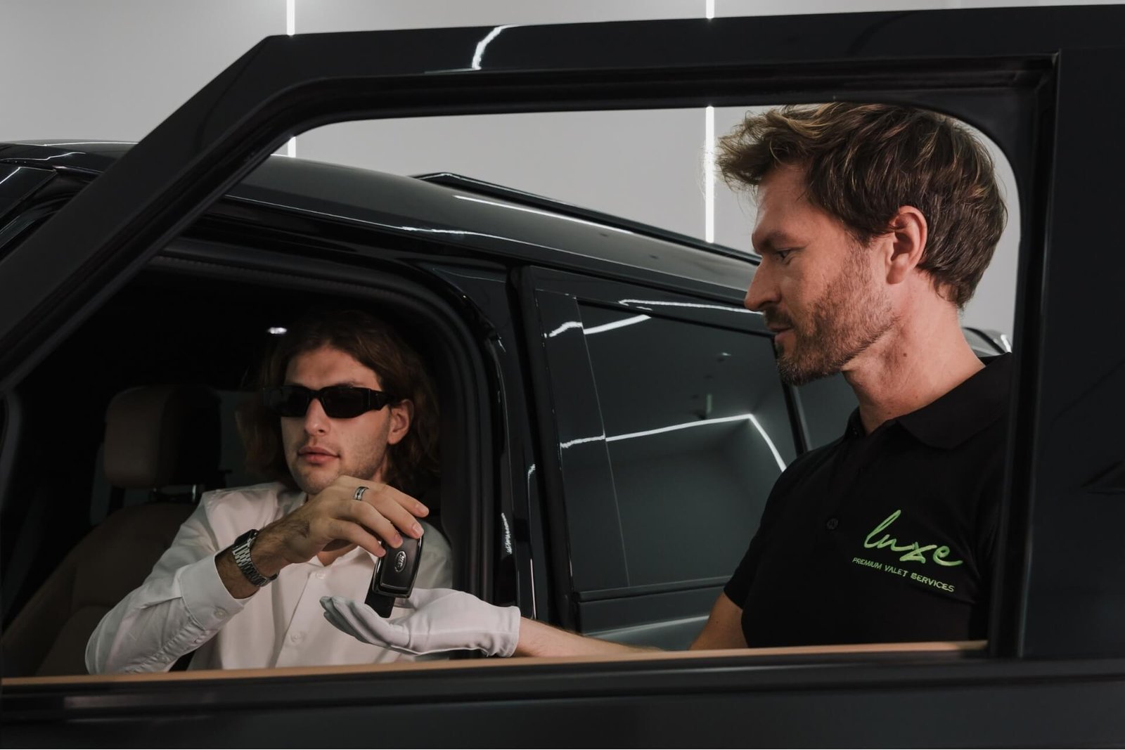 Luxe Valet Services attendant taking the key from a driver seated in a luxury car