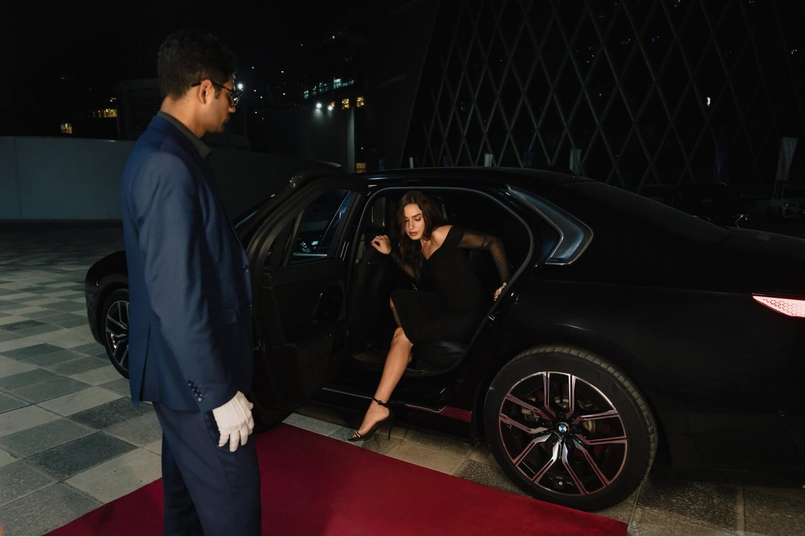 Valet attendant in white gloves holding the car door as a guest steps out onto a red carpet in Dubai